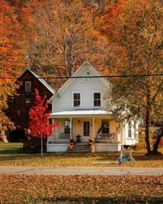 a white house surrounded by trees with fall foliage