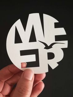 a hand holding up a white sticker with the word me and bird on it