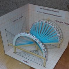 a blue and white paper model of a ferris wheel on a wooden table with rulers