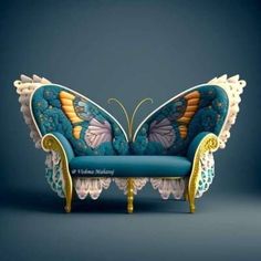 a blue couch with an intricate butterfly design on it's back and wings, sitting in front of a dark background