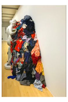 a pile of clothes sitting on top of a wooden floor next to a white wall