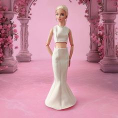 a barbie doll in a white dress standing on a pink floor with flowers behind her