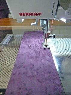 the machine is working on the purple rug that's being sewnged in