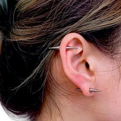 a close up of a person's ear with three piercings on it and one behind the ear