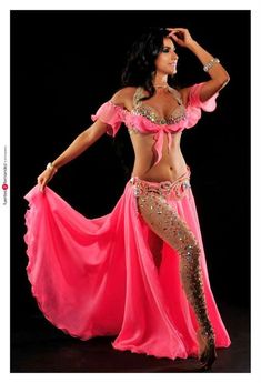 a woman in a pink belly dance outfit posing for a photo with her hands on her hips