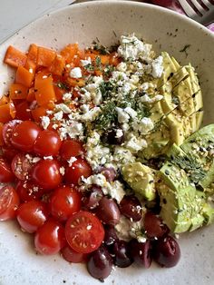 a white bowl filled with lots of different types of food on top of a table