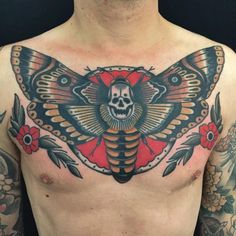 a man's chest with a moth tattoo on it and flowers around the neck