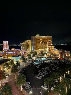 an aerial view of a city at night with cars parked in the parking lot and palm trees