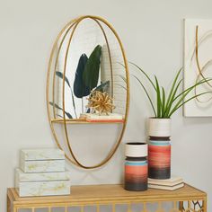 a mirror sitting on top of a wooden table next to vases and plants in front of it