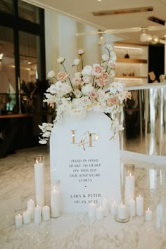 a table with candles and flowers on it in front of a sign that says l p