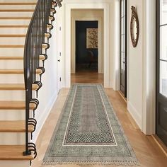 a long hallway with a stair case and rug on the floor in front of it