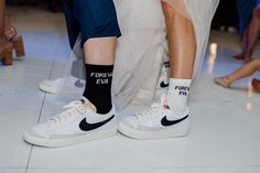 two people wearing white sneakers with black socks