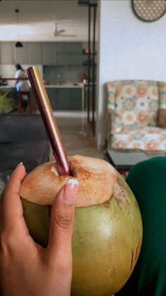 a person holding a green coconut with a stick sticking out of it