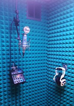 two microphones in front of a blue wall with sound recording equipment on the side