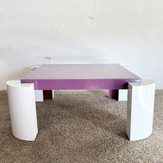 a purple and white table sitting on top of a carpeted floor