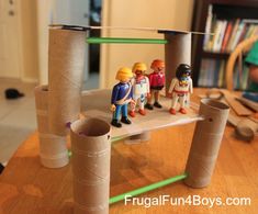 several toy figurines are standing on a table made out of toilet paper tubes