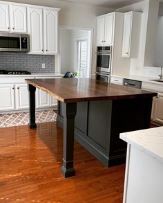 an empty kitchen with white cabinets and wood flooring is pictured in this image from the front view