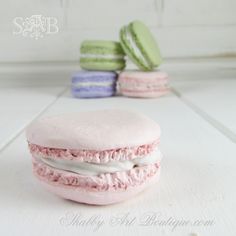 a pink macaroon with white frosting and sprinkles