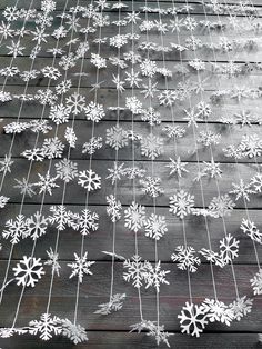 snowflakes are hanging from a wire on a wooden deck with string attached to it