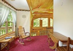 a living room filled with furniture and a wooden rocking chair in front of a window