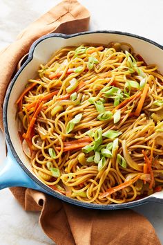 a pan filled with noodles and vegetables on top of a table