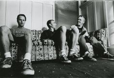 three men sitting on a couch with their legs crossed