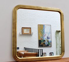 a large mirror sitting on top of a wooden table next to a white brick wall