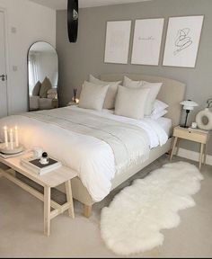 a white bed sitting in a bedroom next to a mirror