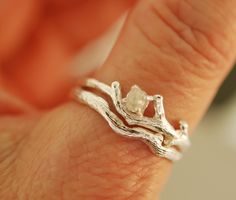 a close up of a person's hand wearing a silver ring with branches on it