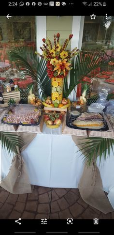 a table with many different types of food on it and palm trees in the background