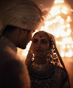 a man and woman standing next to each other in front of a wall full of lights