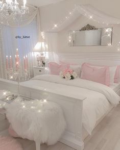 a white bed with pink pillows and lights