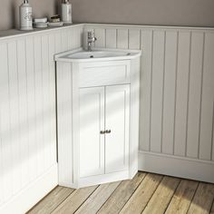 a white bathroom sink sitting next to a wall mounted faucet on a wooden floor