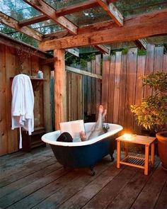 a person laying in a bathtub with their feet up on the floor and reading