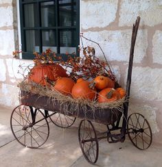 a wagon filled with pumpkins sitting on top of a cement floor next to a window