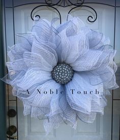 a large white mesh flower on the front door of a house with words noble touch above it