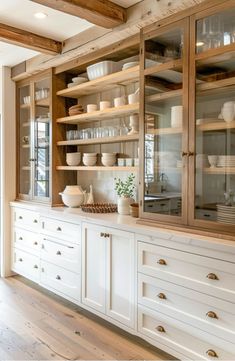 a kitchen with white cabinets and glass doors on the front, open shelving above