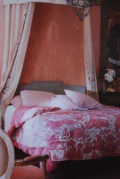 a bed with pink sheets and pillows in a room