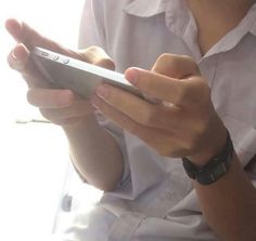 a close up of a person holding a cell phone in their hands and looking at the screen