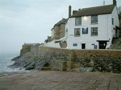 a white building sitting on the side of a cliff next to the ocean in front of some buildings