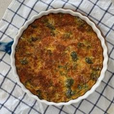 a casserole dish with broccoli in it on a blue and white checkered cloth