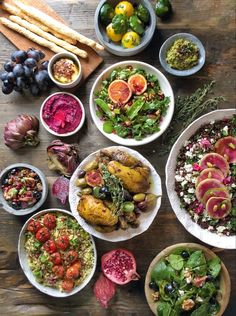 a table topped with lots of different types of food next to bowls of salads