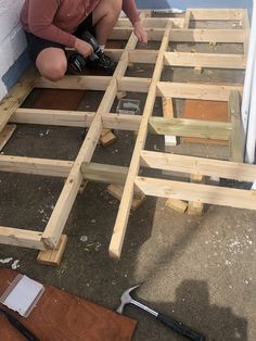 a man kneeling down on the ground working on some wooden framing for a house wall