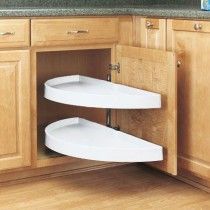 two white plates are sitting in the corner of a kitchen cabinet with wood floors and wooden cabinets