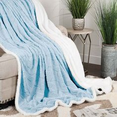 a blue and white blanket sitting on top of a couch next to a potted plant