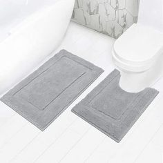 two gray bath mats sitting next to a white toilet