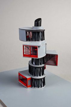 an architectural model of a building with red and white trim on the top floor, in front of a gray background