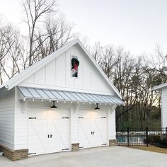 two white garages with lights on the roof and one has a christmas wreath hanging from it