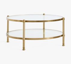 a glass and brass coffee table with two shelves on the bottom one shelf is round