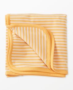 an orange and white striped blanket folded on top of each other with a yellow border